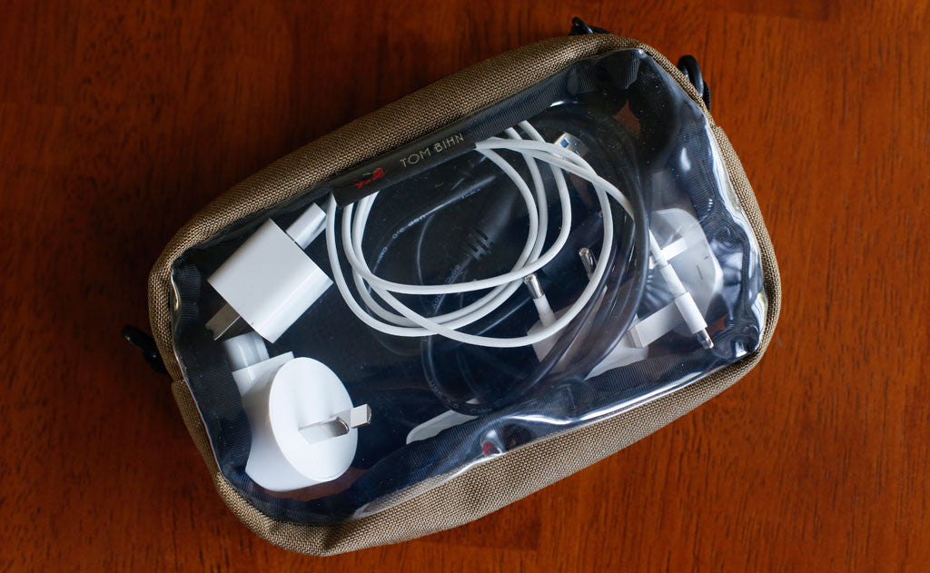 detail visible^^A 3D Clear Organizer cube holding charging cables and travel plug adapters.