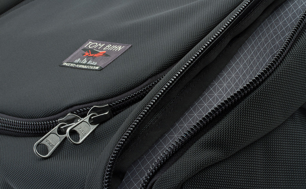^^The label of the bag is offset to the right near the bottom of the main pocket's fabric lid. It features a red Farman Jaribu plane over a cityscape and the words "Portable Culture" embroidered near the bottom.