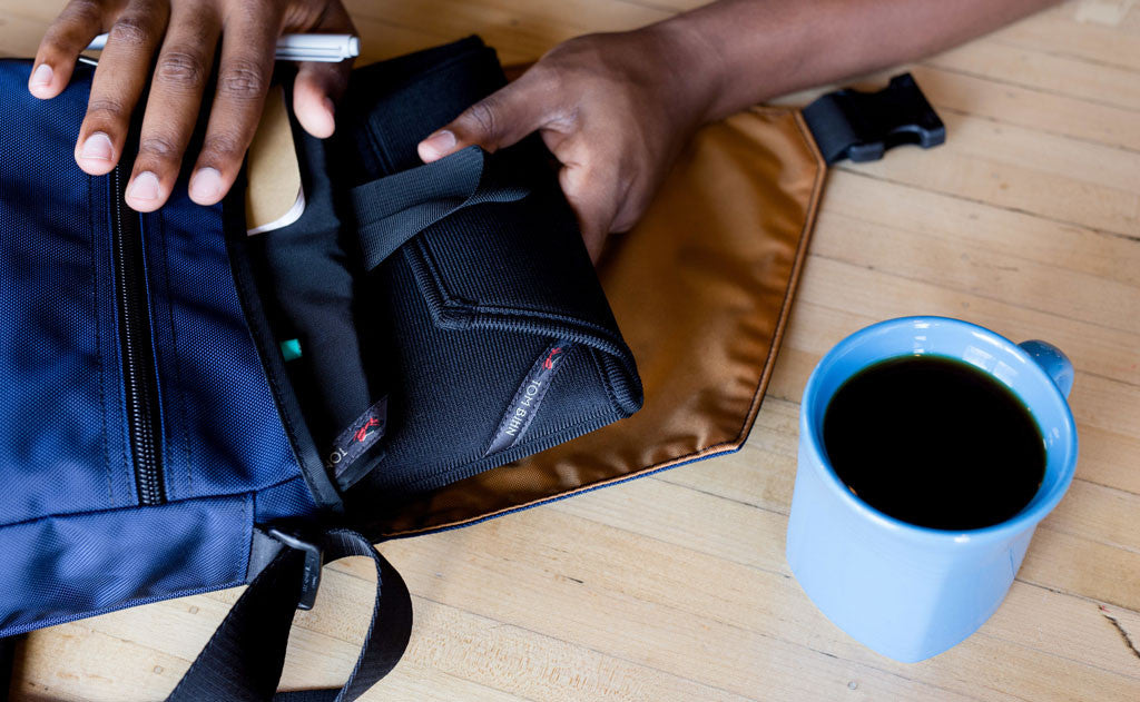 A person pulling a Cache out of the main compartment of the Medium Cafe Bag