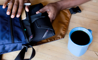A person pulling a Cache out of the main compartment of the Medium Cafe Bag