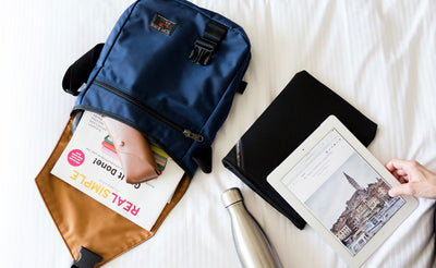 A person with the Medium Cafe Bag while reading an e-reader.