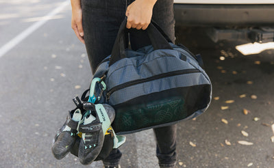 visible detail^^Person holding an OSCA that has some climbing shoes attached via a carabiner to the shoulder strap attachment point.