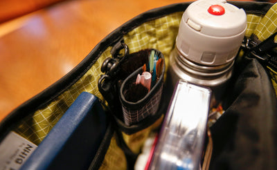 A close shot of the interior of the Maker's Bag, packed with a water bottle, painting tools, and a notebook.