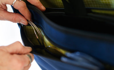 ^^A person removing a cable knitting needles from the front pocket of a Maker's Bag.