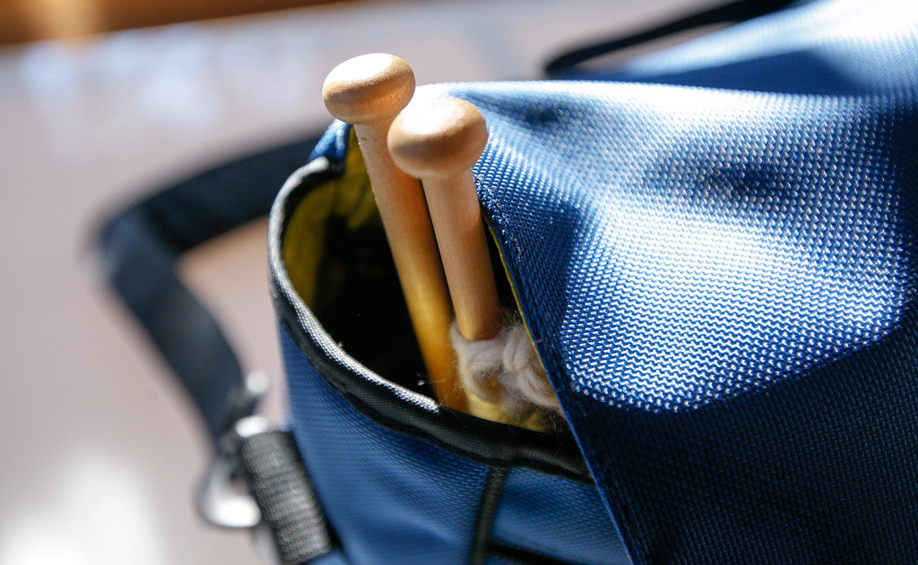 ^^A pair of large, wooden knitting needles being carried in the Maker's Bag..