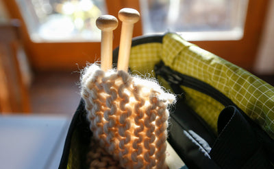 ^^A pair of large knitting needles and a knitting project stored in a Maker's Bag.