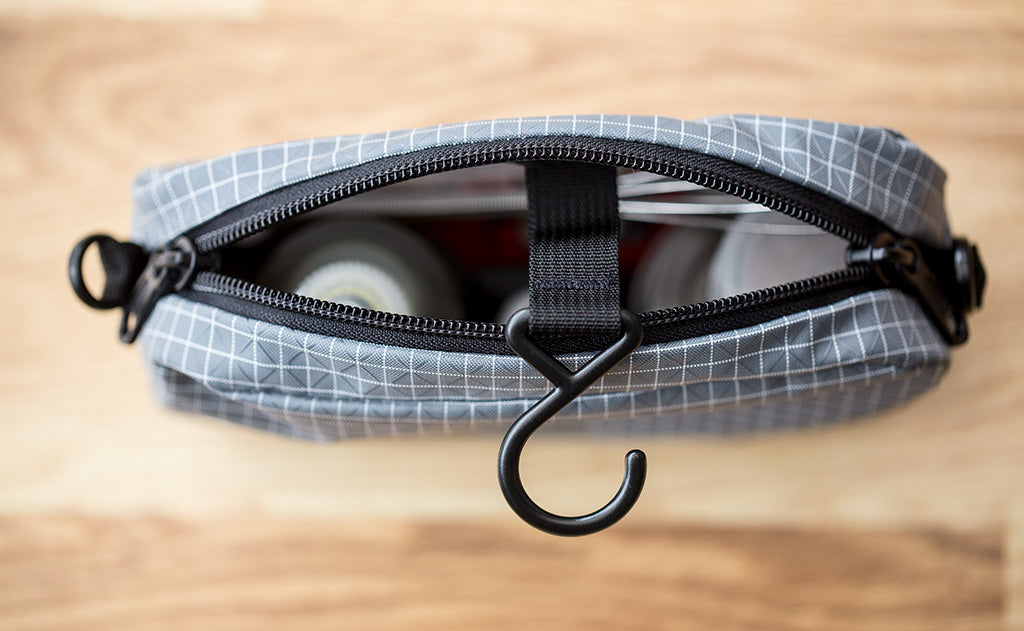 lifestyle visible^^An assortment of items in a 3D Organizer Cube with the zipper open and hanger hook out.