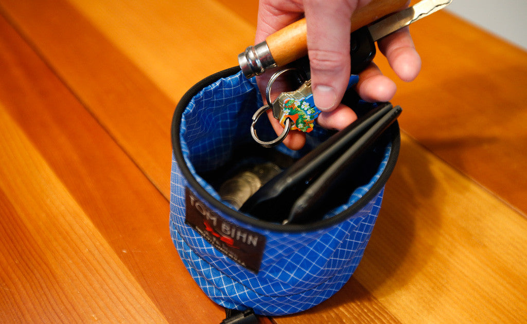 ^^A person placing a pair of keys into a Small Travel Tray holding a wallet and some change.