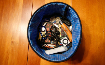 visible detail^^A Small Travel Tray holding a pair of headphone, a few tubes of lotion, and a pocket phrasebook.