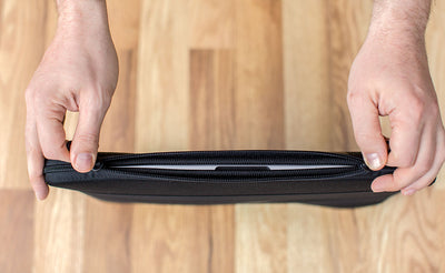detail visible^^A laptop in a Cache being opened on the horizontal zipper side.