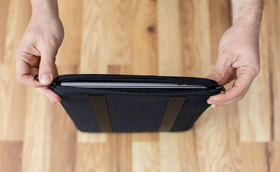 detail visible^^A laptop in a Cache being opened on the vertical zipper side.