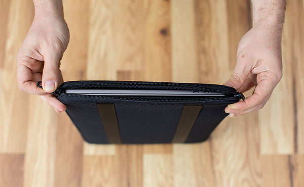 A laptop in a Cache being opened on the vertical zipper side.