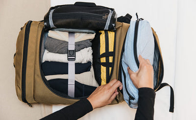 lifestyle visible^^Packing Cube Shoulder Bag in Acuity being packed in an Aeronaut 45 in Coyote.