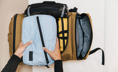 lifestyle visible^^Packing Cube Shoulder Bag in Acuity being packed in an Aeronaut 45 in Coyote.
