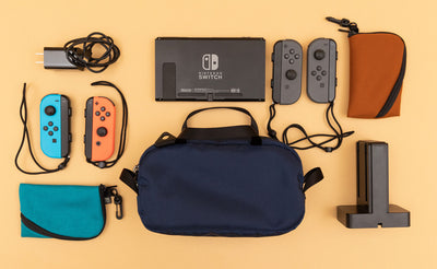 detail visible^^ A Navy Parapack Grab Bag with Nintendo Switch and accessories next to it, including two Mini Ghost Whale Pouches.