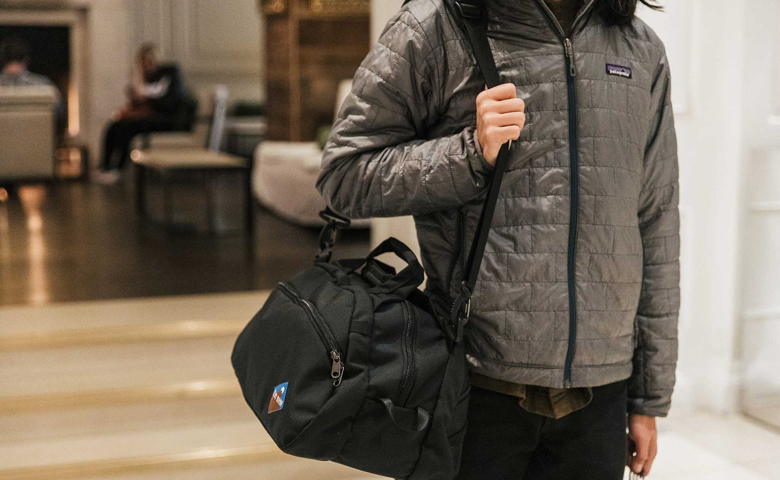 visible lifestyle^^Person carrying a Black OSCA on their shoulder walking through a hotel lobby.