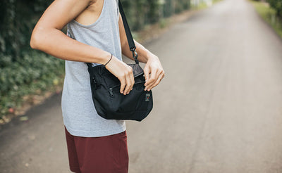 ^^A person accessing the Packing Cube Shoulder Bag's front zipper while wearing it cross-body.