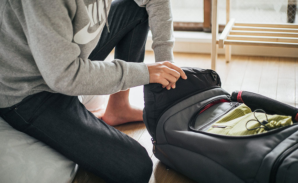 ^^A person slipping a Packing Cube Shoulder Bag into an Aeronaut 45.