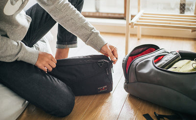 ^^A person zipping closed a Packing Cube Shoulder Bag.