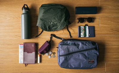 ^^A possible loadout of a Packing Cube Shoulder Bag (a rain shell, a Q-Kit with loose change, a water bottle, a wallet, a glasses case, chapstick, and a notepad and paper 3-fold map).