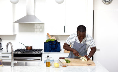 lifestyle visible^^A person chopping vegetables with The Truck full of groceries on the counter behind them.