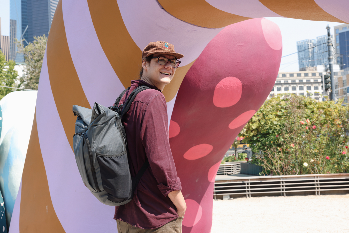 Person wearing the Adept Roll-Top Backpack on their back, smiling at the camera.