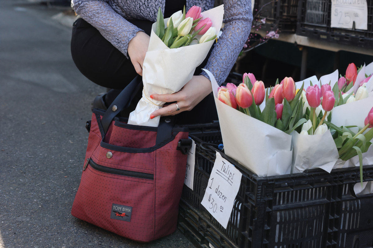 Person putting a bouquet of tulips into their 420D Spectron Bordeaux Forager at the Farmers Market. 