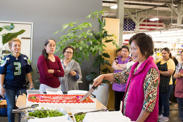 Di cutting a cake to share with the rest of the TOM BIHN crew