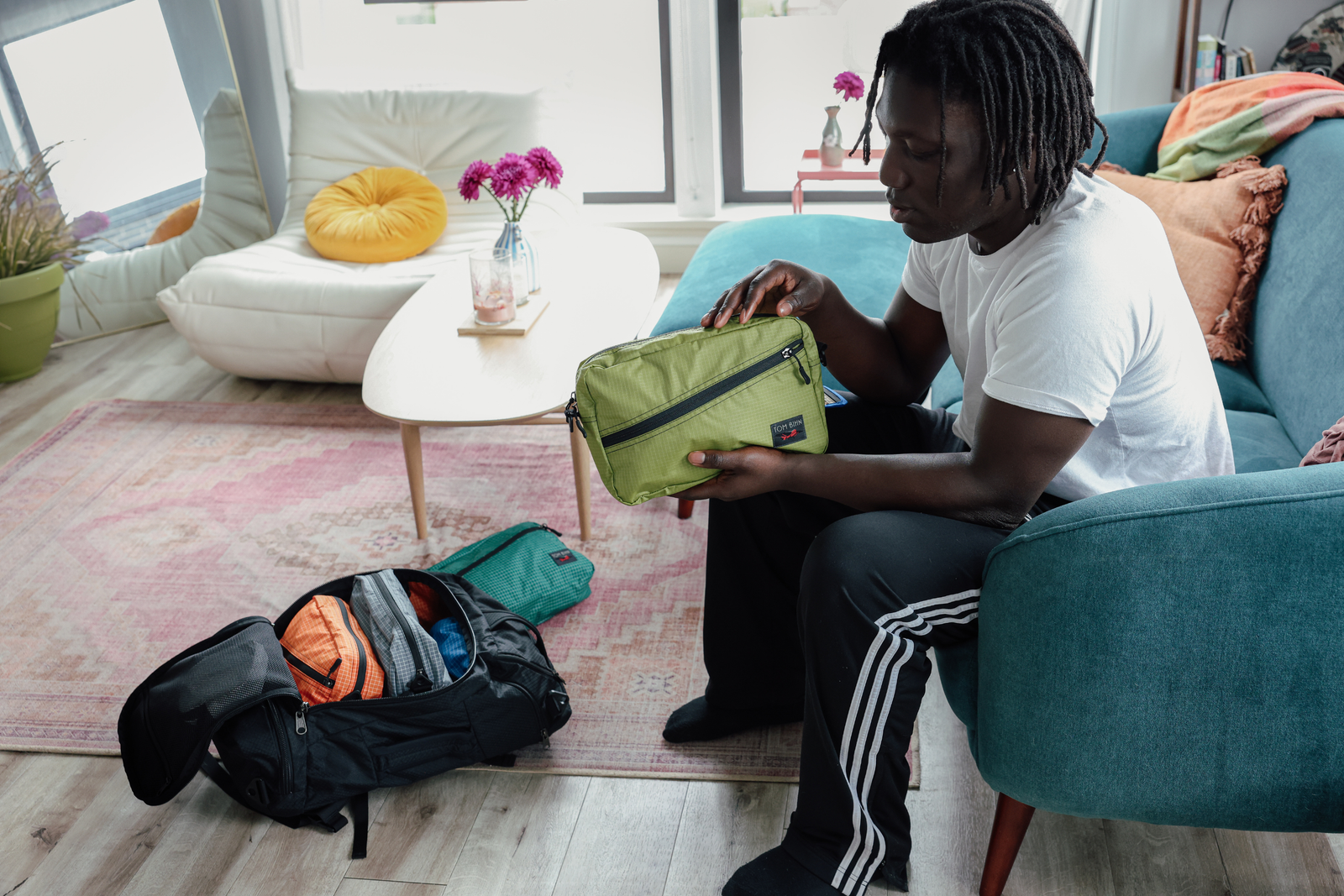 Man holds Packing Cube Shoulder Bag in Moss Cerylon, packed in Black Spectron t45 with various other Packing Cube Shoulder Bags.