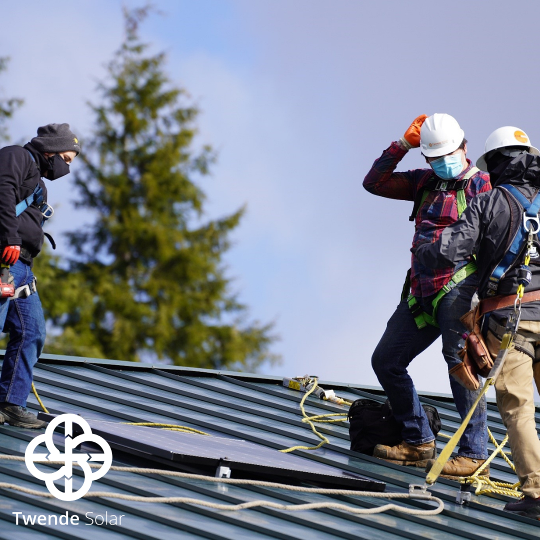 Construction workers installing a solar panel on a roof top.