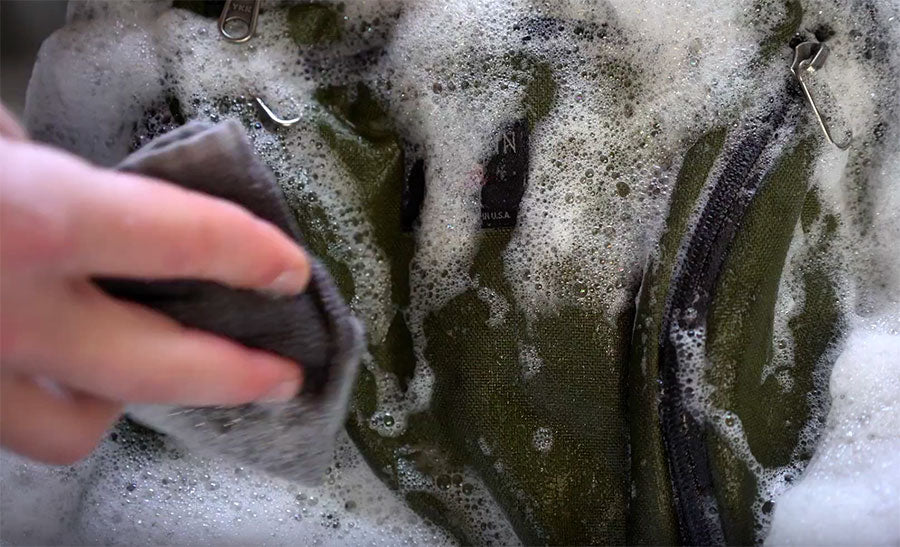 A TOM BIHN bag being washed with lots of soap and suds. 