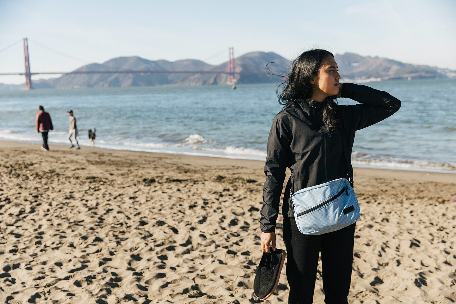 A person walking on the beach with an Acuity Packing Cube Shoulder Bag.