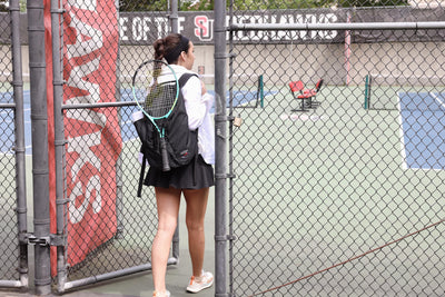 visible lifestyle^^A person carrying a Smart Alec 2.0 with a tennis racquet attached to the front.