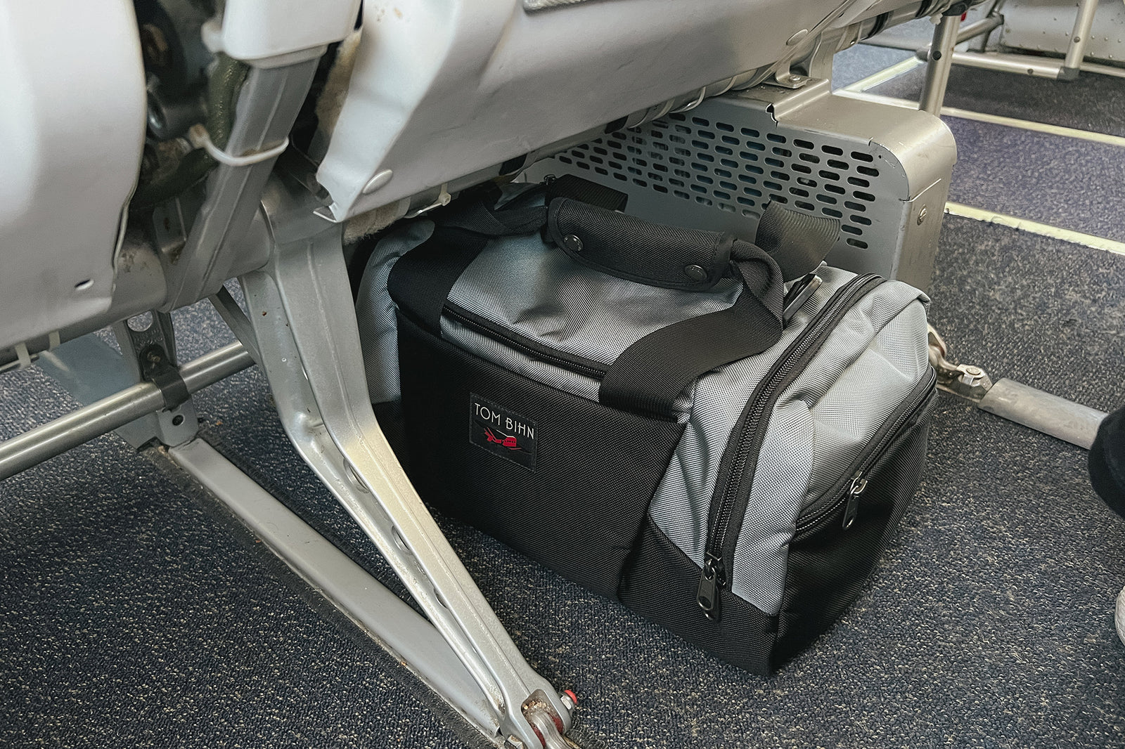 visible lifestyle^^Night Flight Travel Duffel under the seat lengthwise on a plane.