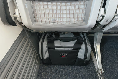 visible lifestyle^^Night Flight Travel Duffel under the seat widthwise on a plane.