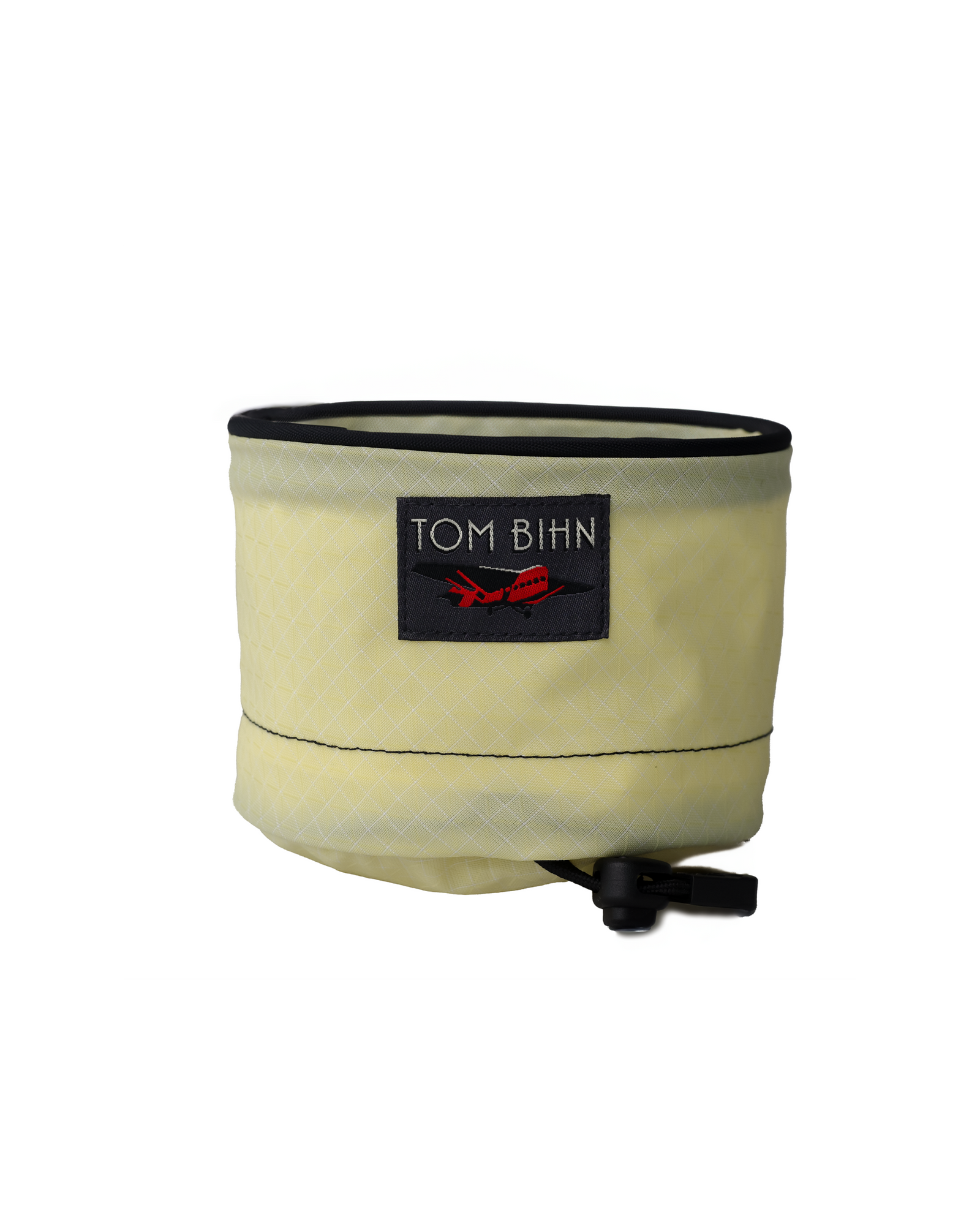 lemonade yellow folding tray with black rim and adjustable strap on a white background, featuring Tom Bihn logo.