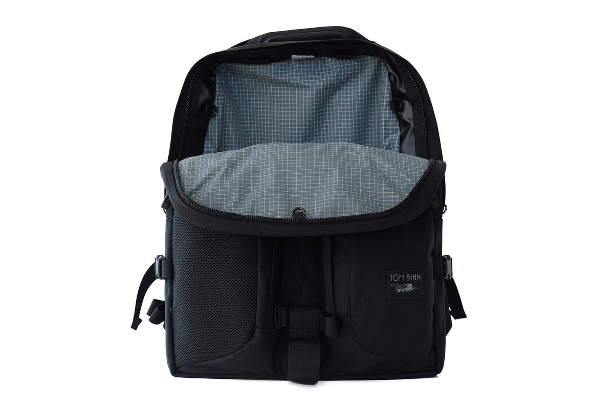 visible variant TB0114-BKND^^The Brain Bag in Black Ballistic with the front main compartment zipper opened to reveal its Northwest Sky (grey with white grid) 200 Halcyon interior.