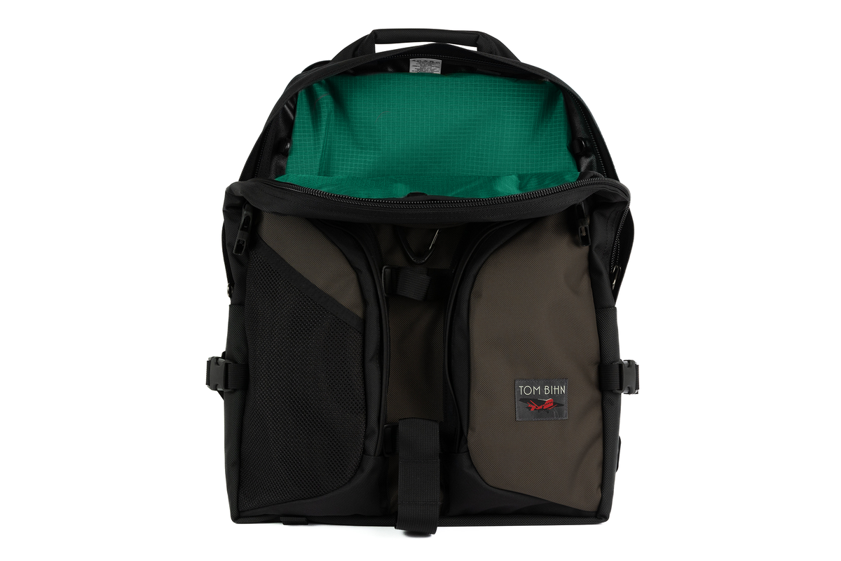 visible variant TB0114-RKEL^^The Brain Bag in Ursa (brown-grey) Ballistic with the front main compartment zipper opened to reveal its Emerald (dark green with green grid) 210 Cerylon interior.