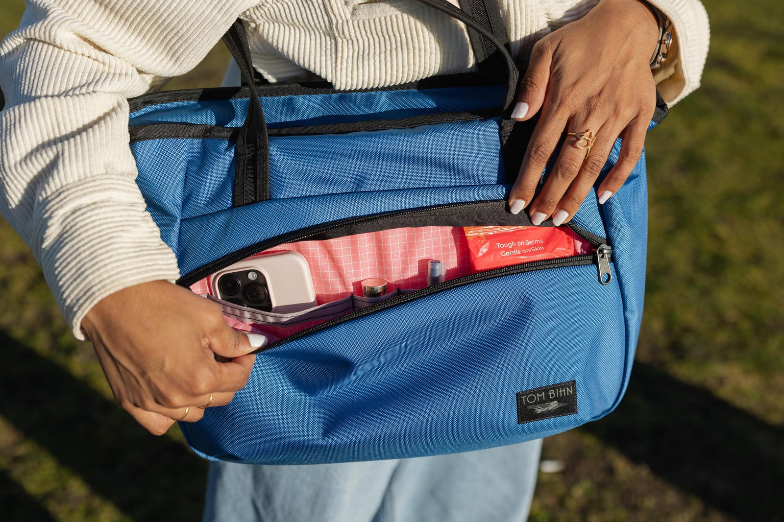 visible lifestyle^^A Nomad Tote with its front pocket open.