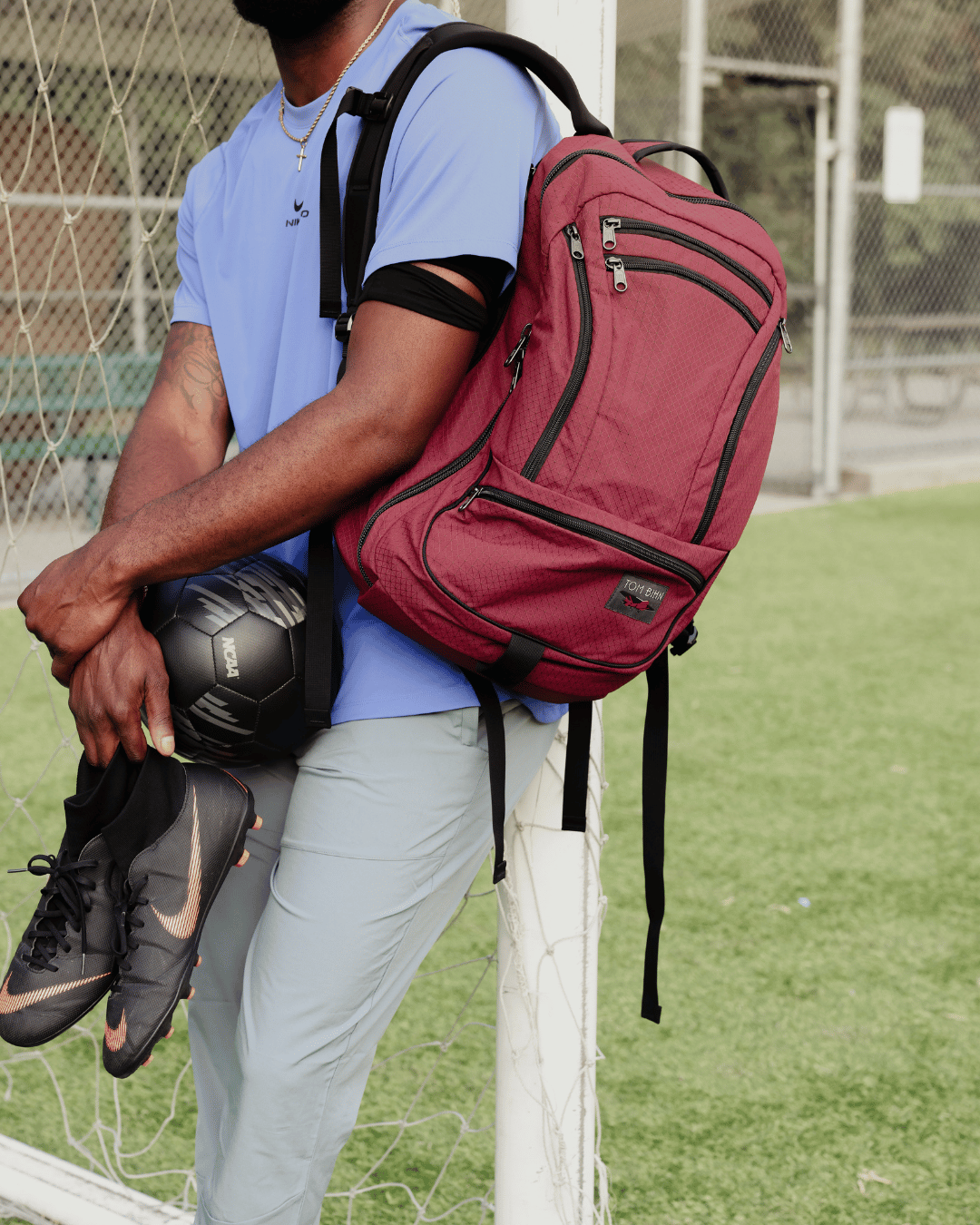 visible lifestyle^^ A person wearing Synik 30 over one shoulder with soccer ball and cleats in hand.