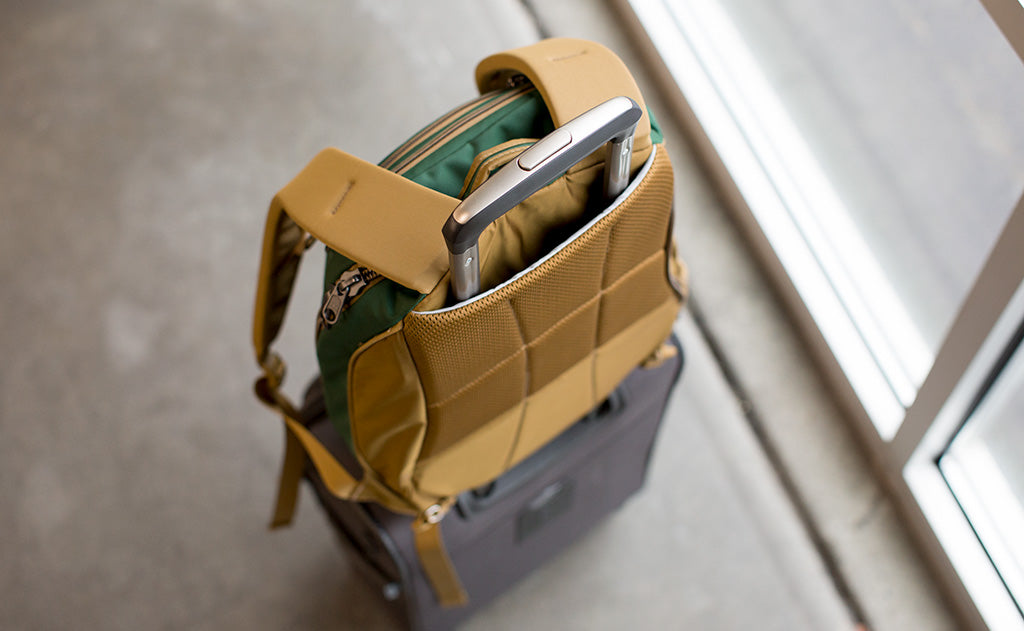 lifestyle visible^^The Guide's Edition Synik 22 on the handle of roll-aboard suitcase held in place by its luggage handle passthrough.