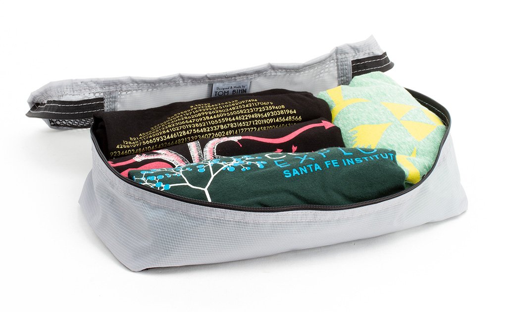 visible variant TB90500-NE^^An open Northwest Sky (light grey) Aether Aeronaut 30 Small Packing Cube holding four shirts.