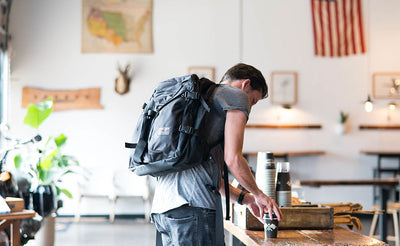 lifestyle visible^^A person getting coffee at a coffee shop while wearing a Brain Bag.