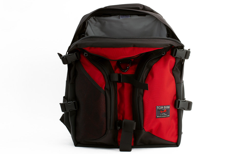 visible variant TB0104-MKLJ TB0114-MKLJ^^The Brain Bag in Mars Red 525 Ballistic with the front main compartment zipper opened to reveal its Cloud (light grey) 210 Ballistic interior.
