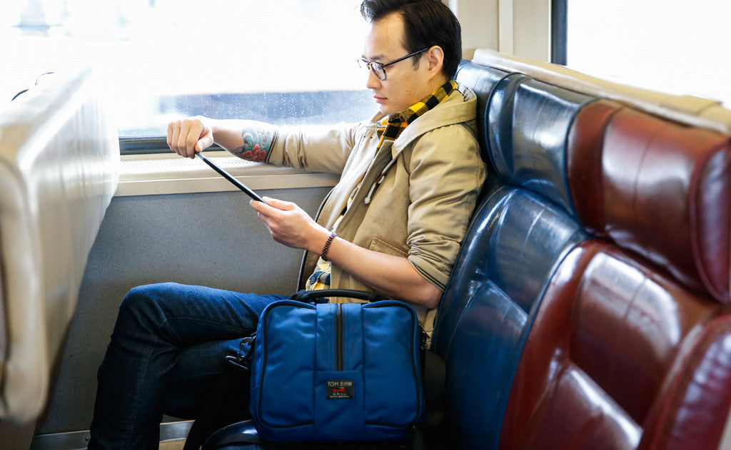 lifestyle visible^^Person sitting in the window seat of a train looking at their tablet while the Co-Pilot is next to them.