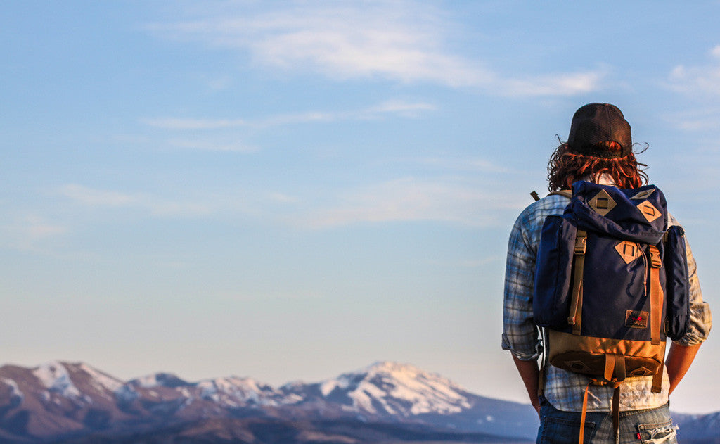 lifestyle visible^^A person wearing a Guide's Pack at the summit of a mountain.