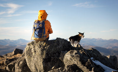 lifestyle visible^^A person sitting at the summit of a mountain wearing the Guide's Pack.
