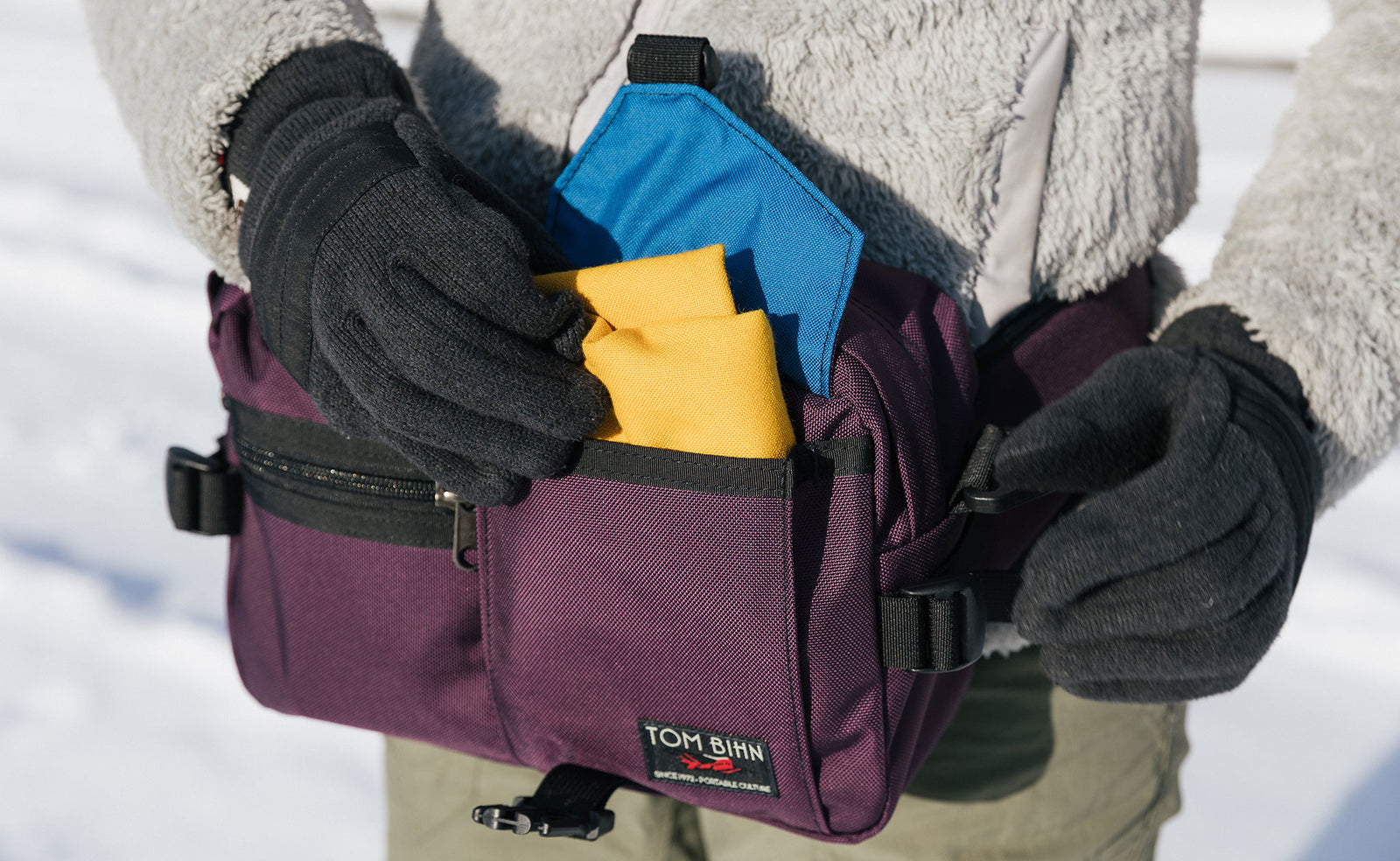 lifestyle visible^^Person wearing winter gloves pulling a scarf out of the front pocket of the LPD.