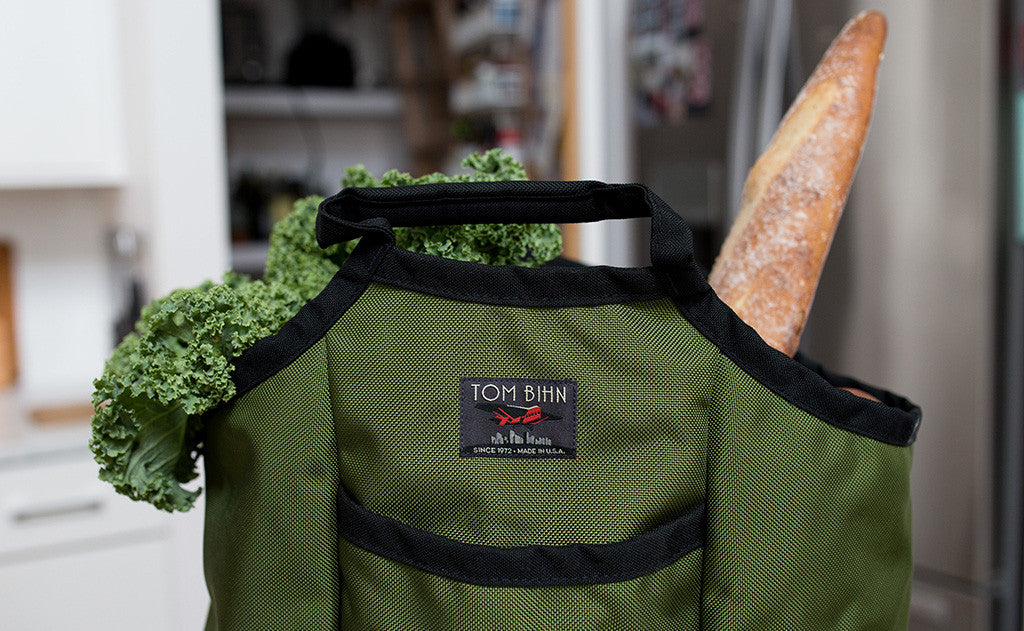 lifestyle visible^^A Moveable Feast holding fresh greens and a baguette.