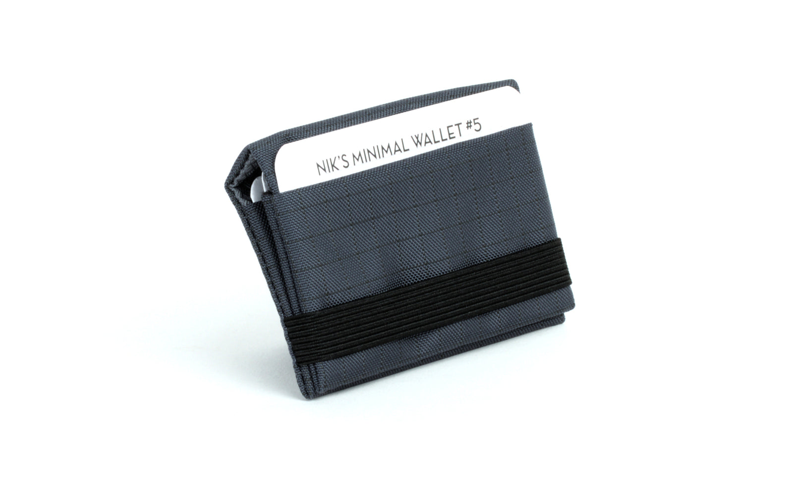 visible variant TB1275-TH^^The Size 5 Nik's Minimalist Wallet in Night Walk (dark blue with grey grid) 400 Halcyon closed with the attached elastic band.